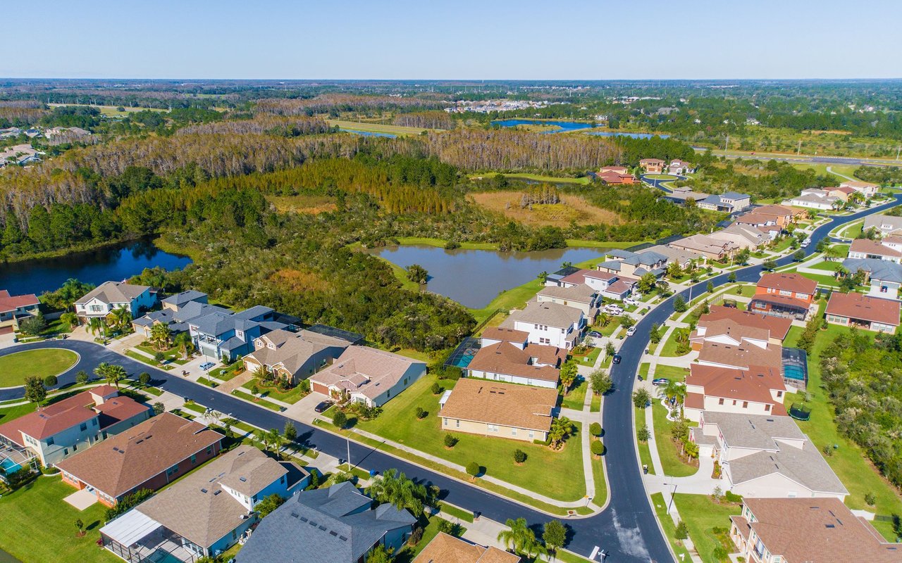 Aerial view of homes beside ponds and a wooded wetland.