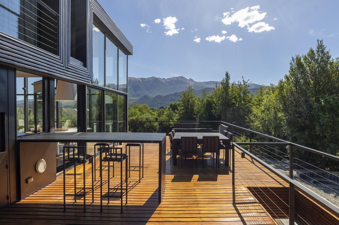 Modern home’s timber deck with outdoor dining and mountain views