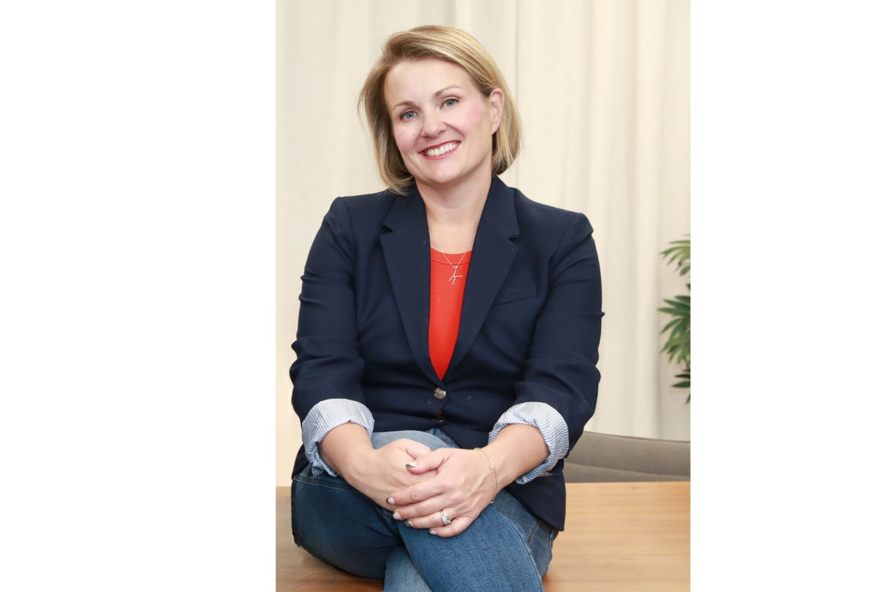 Kate Raftery seated in a navy blazer and red top.