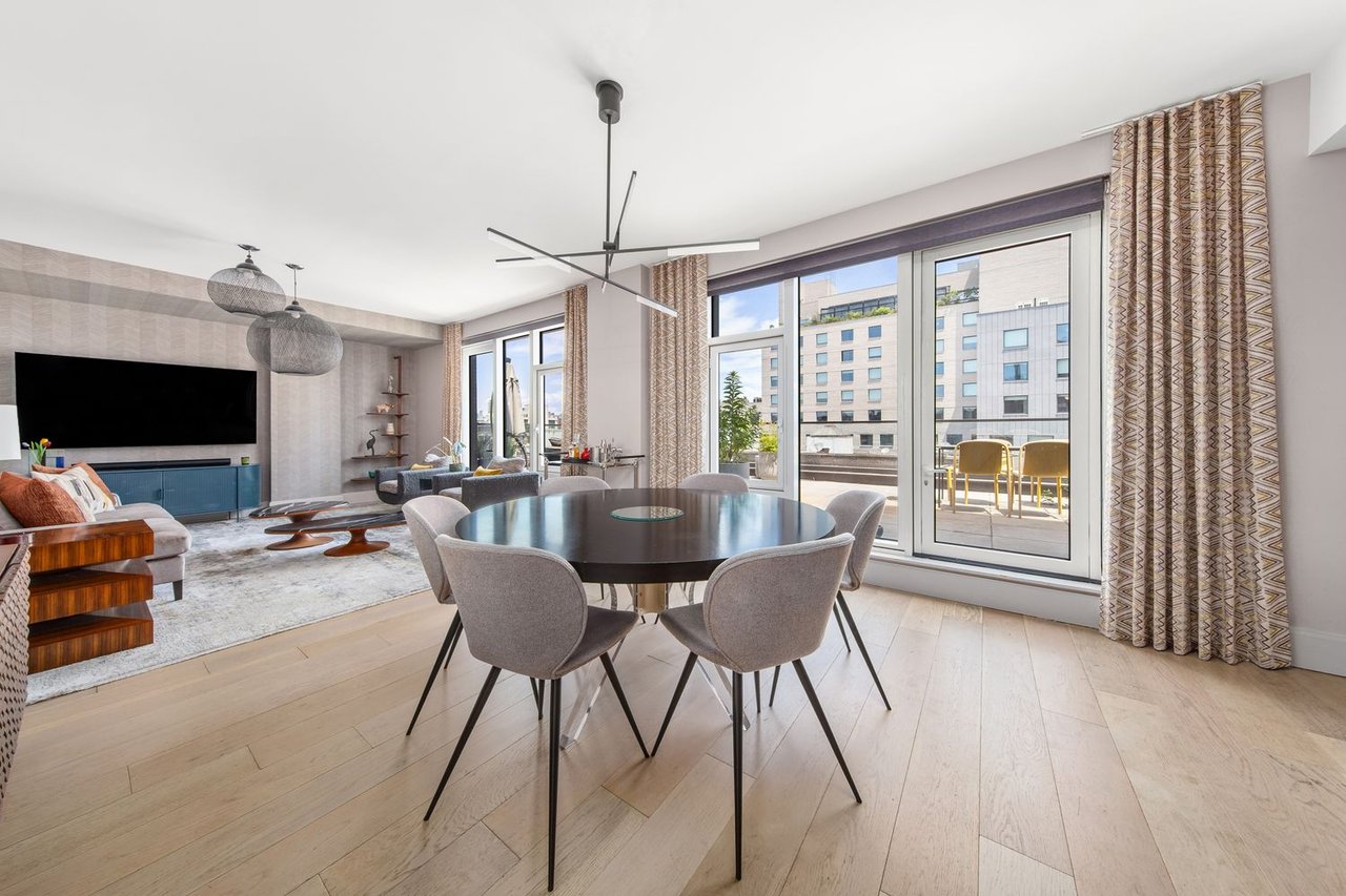Open-plan living and dining room with a round table and large windows overlooking a balcony.