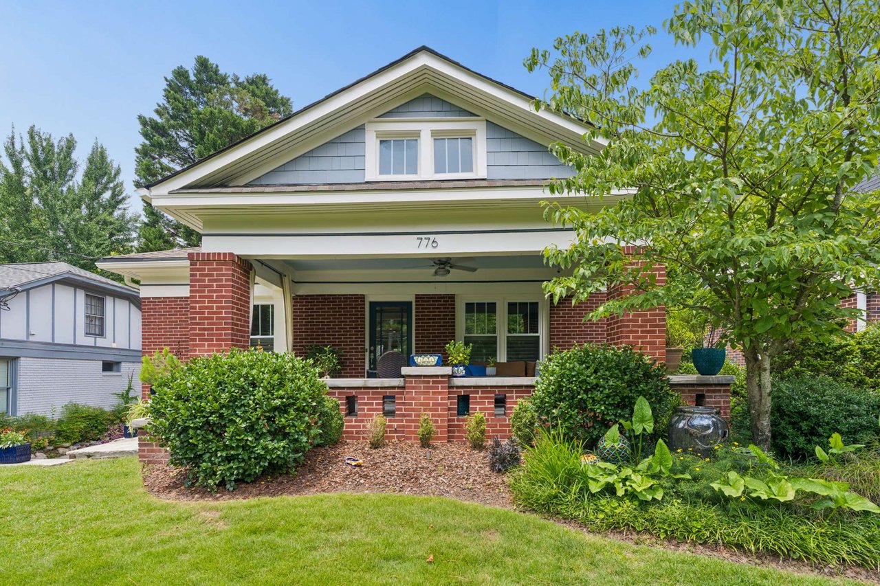 Brick bungalow with a covered porch, white-trimmed gable, and landscaped front garden.