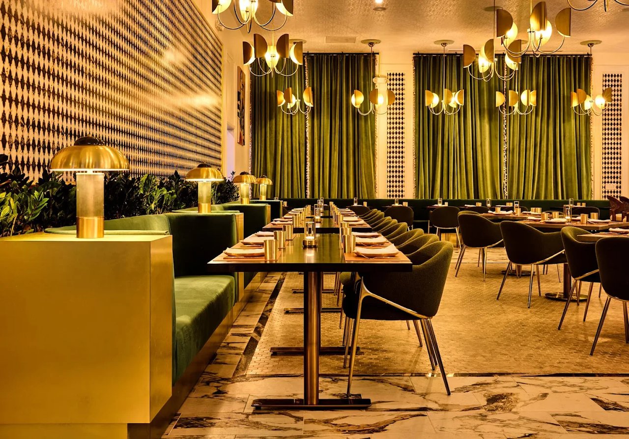 Elegant dining room interior at Pippal in Dublin, California, featuring green velvet booth seating, brass lighting, and patterned wall accents