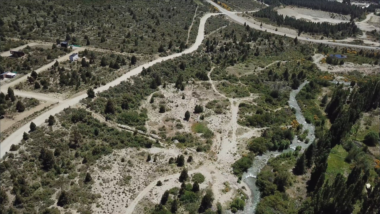 Aerial view of scrubland beside a winding river, crossed by dirt roads.