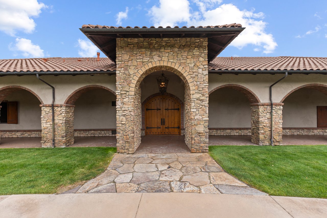 Barn entrance with a stone arch, wooden double doors, and covered arcades.