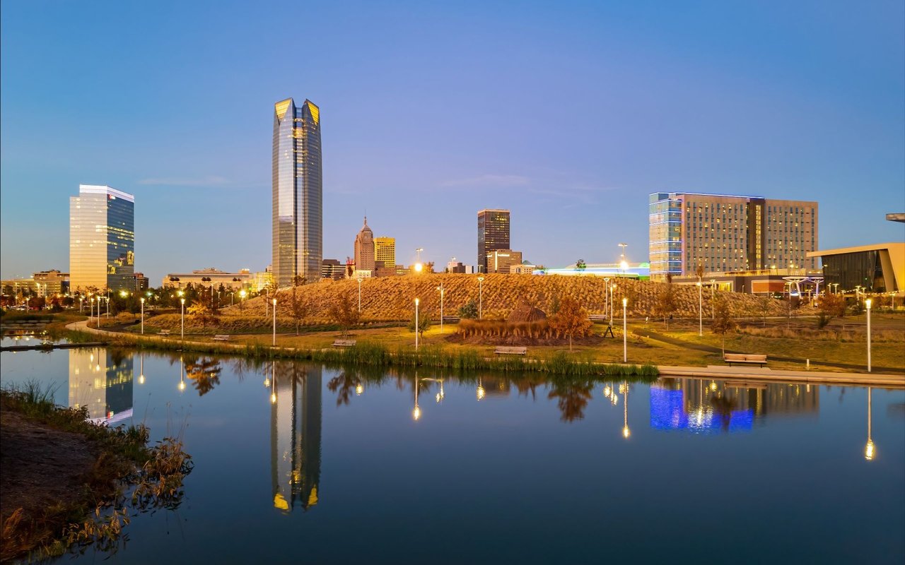 Oklahoma City skyline at dusk, with Devon Tower and downtown lights reflected in the water.
