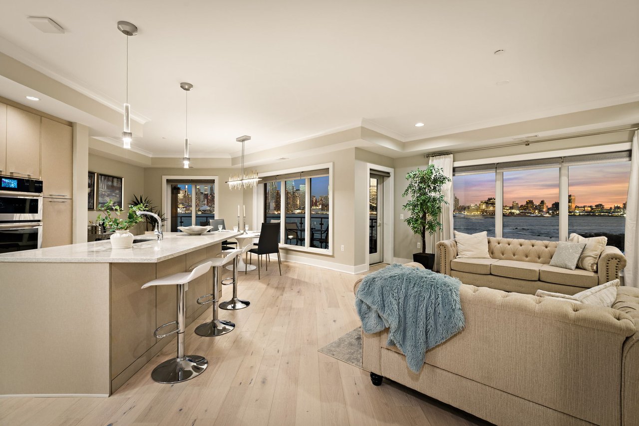 Bright living room with large windows, plush sofas, and stunning NYC skyline views.