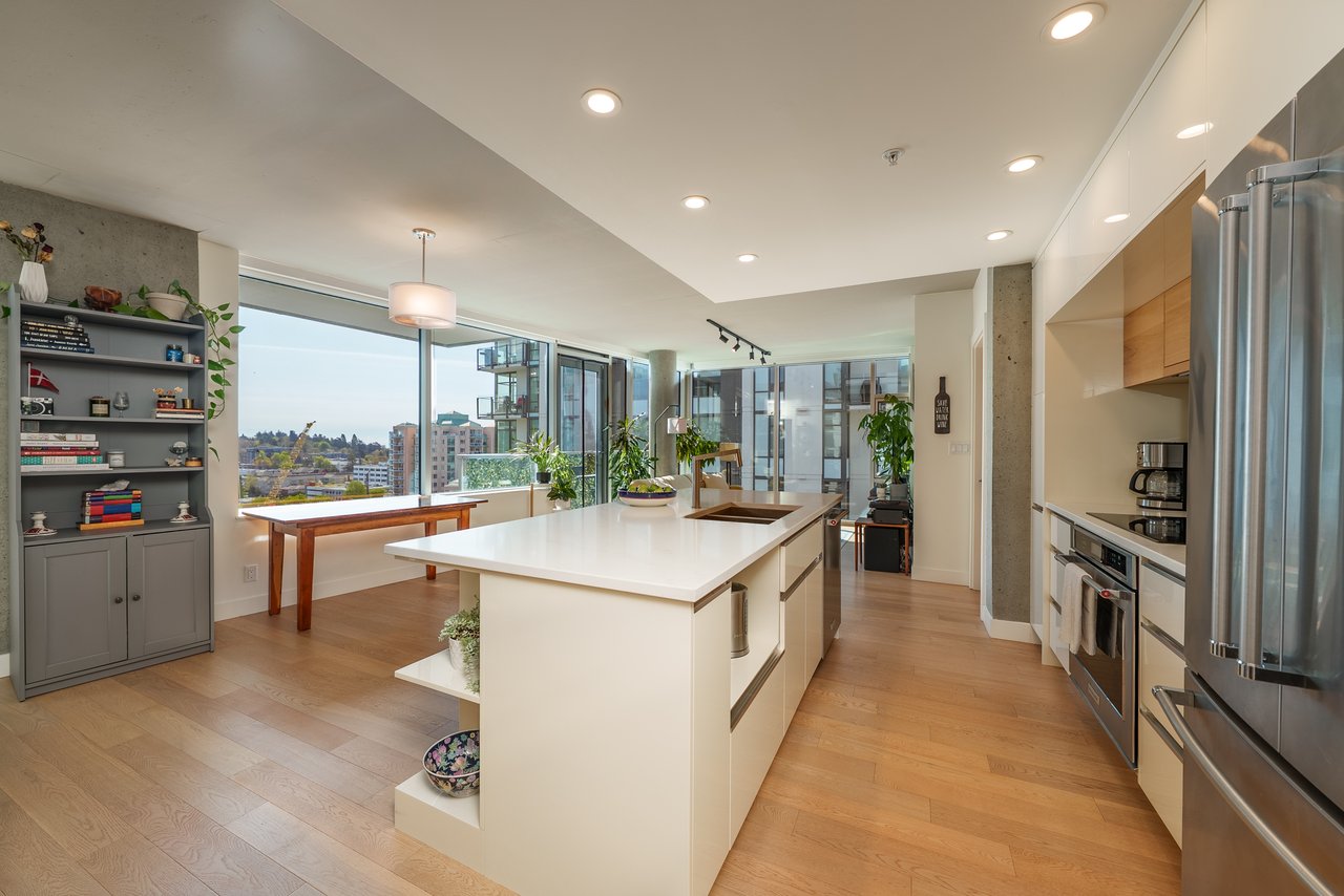 Spacious open-concept kitchen and dining area with large windows and natural light in a Victoria property.