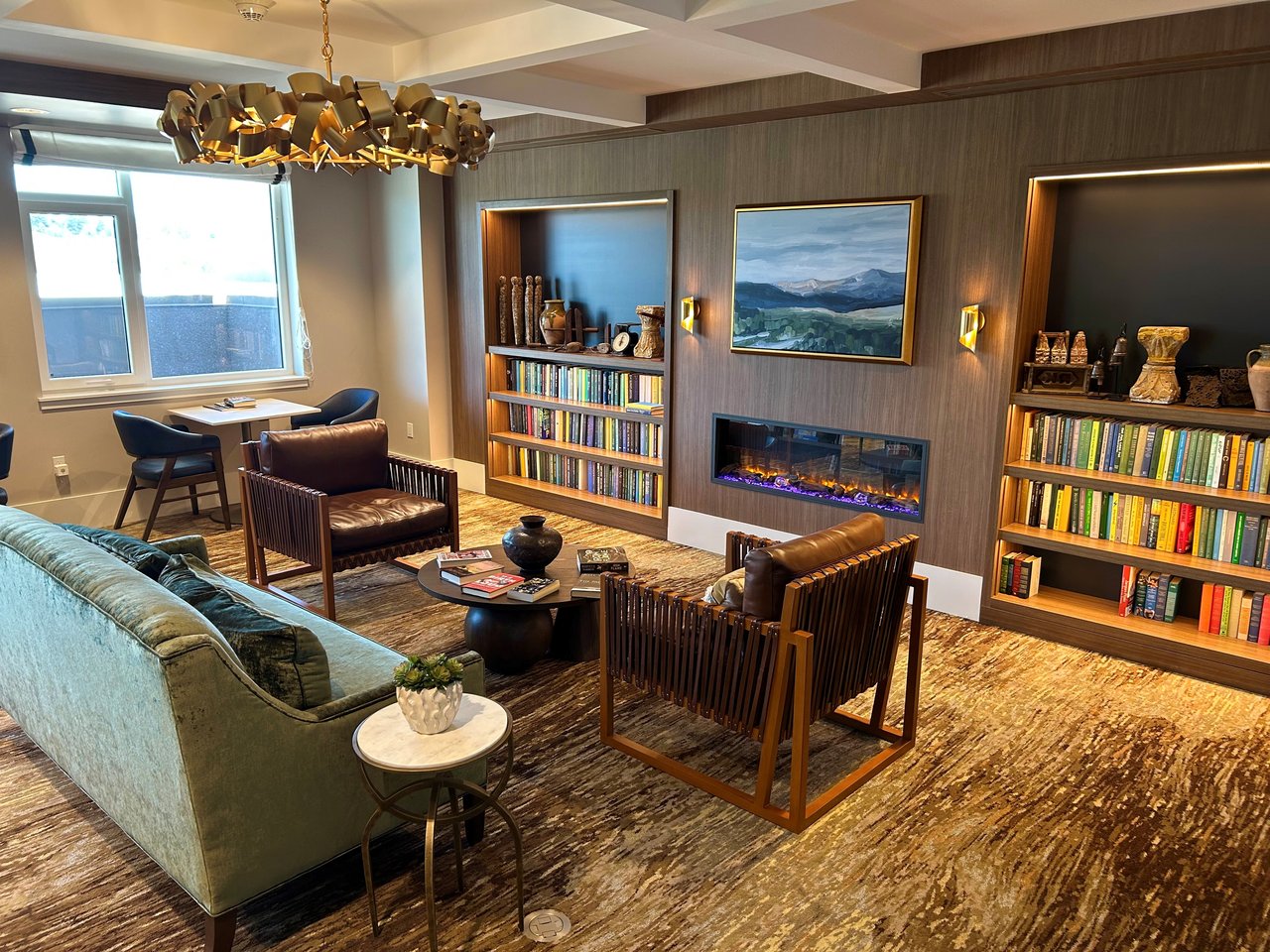 "Resident library lounge with fireplace and bookshelves at Belmont Village San Ramon"