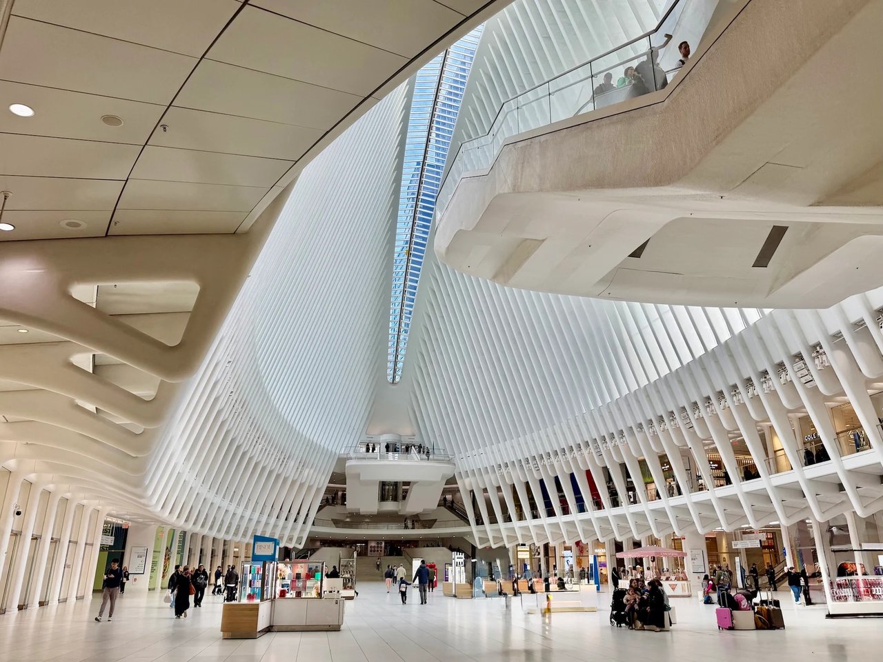 Interior of the Oculus, with sweeping white ribbed arches and visitors on the concourse.