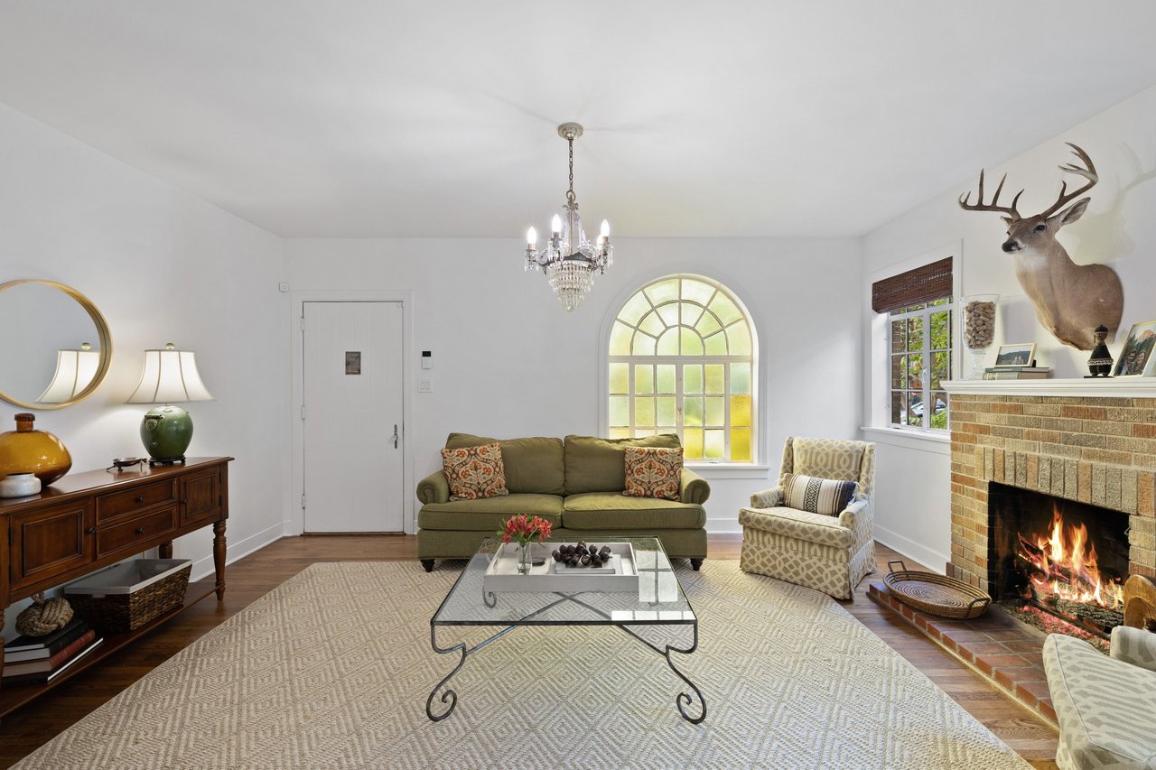 Living room with an olive-green sofa, arched window, and brick fireplace.