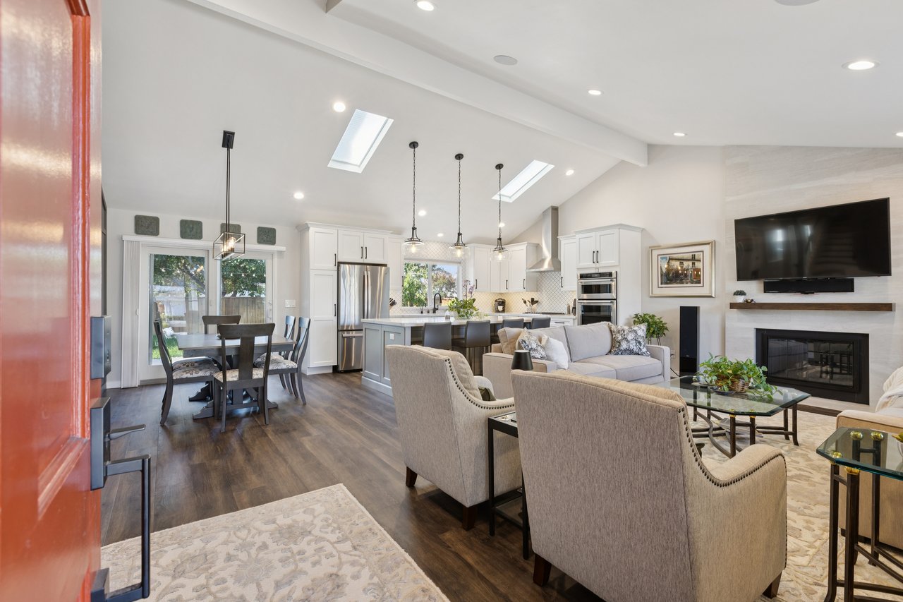 Open-plan living room, kitchen and dining area with skylights and a fireplace.