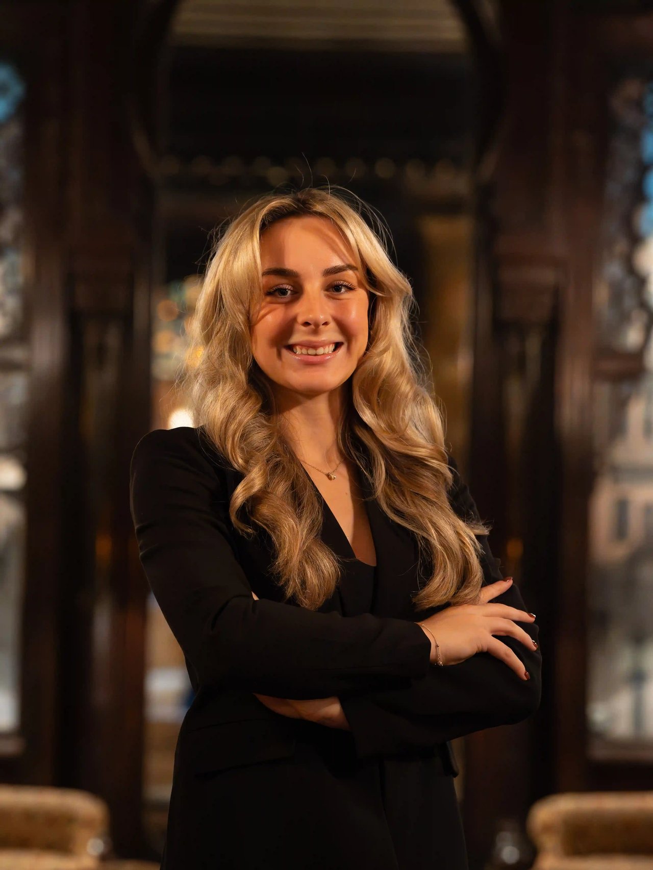 Bri Unger, Director of Operations for the Luxe Haven Group, smiling with arms crossed inside an elegant interior.