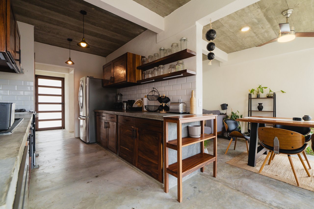 Kitchen and dining area with dark wood cabinets, a central island, and a wood dining table.