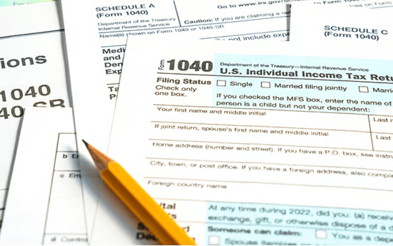 Blank Form 1040 tax paperwork with a yellow pencil resting across the forms.