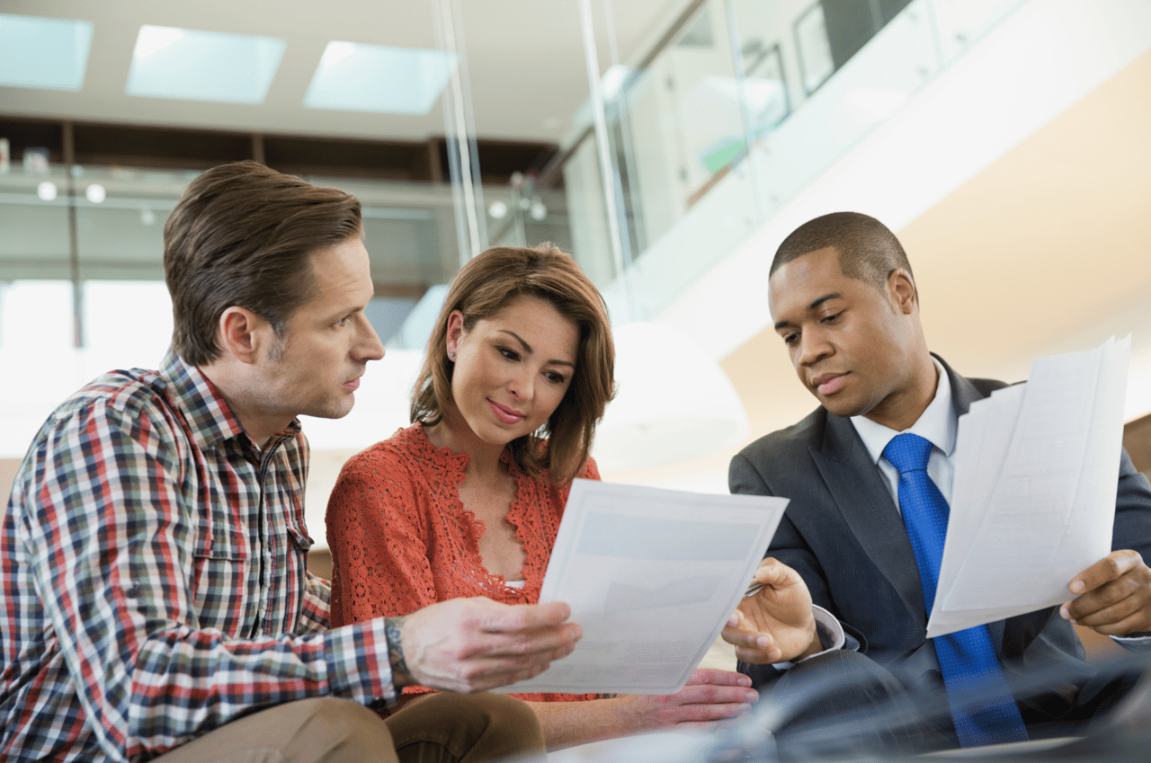 Homebuyers reviewing loan documents while discussing mortgage options