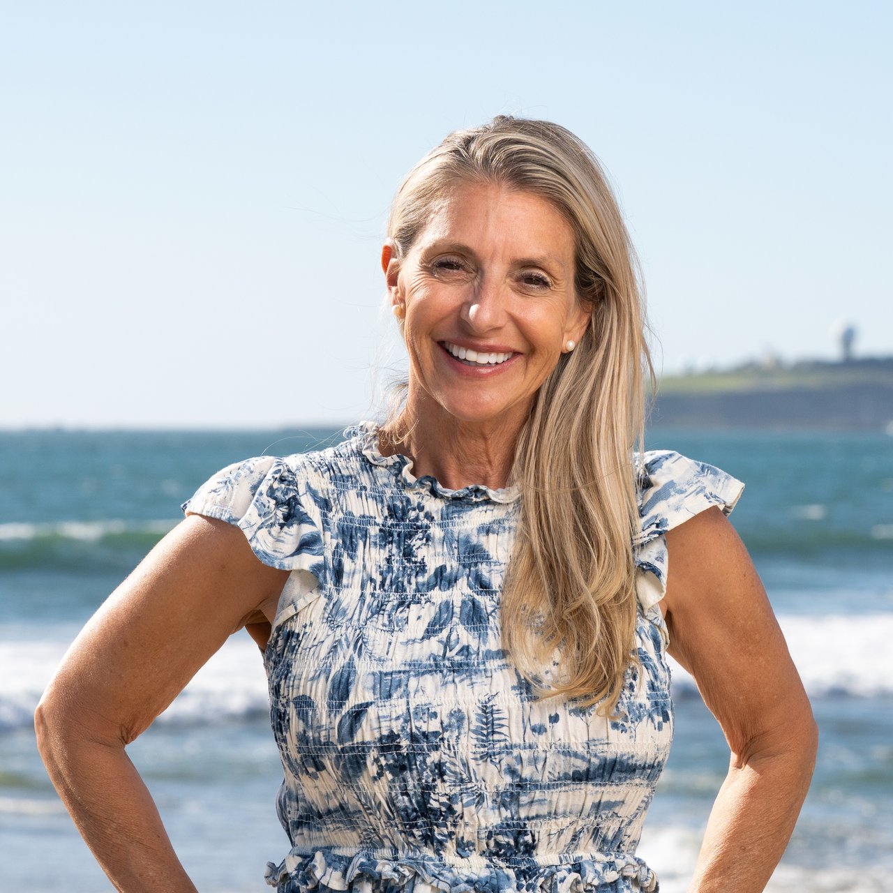 Mishelle Westendorf, real estate agent and relocation specialist with Ocean Element Real Estate, standing on a beach in Half Moon Bay along the San Mateo County Coastside