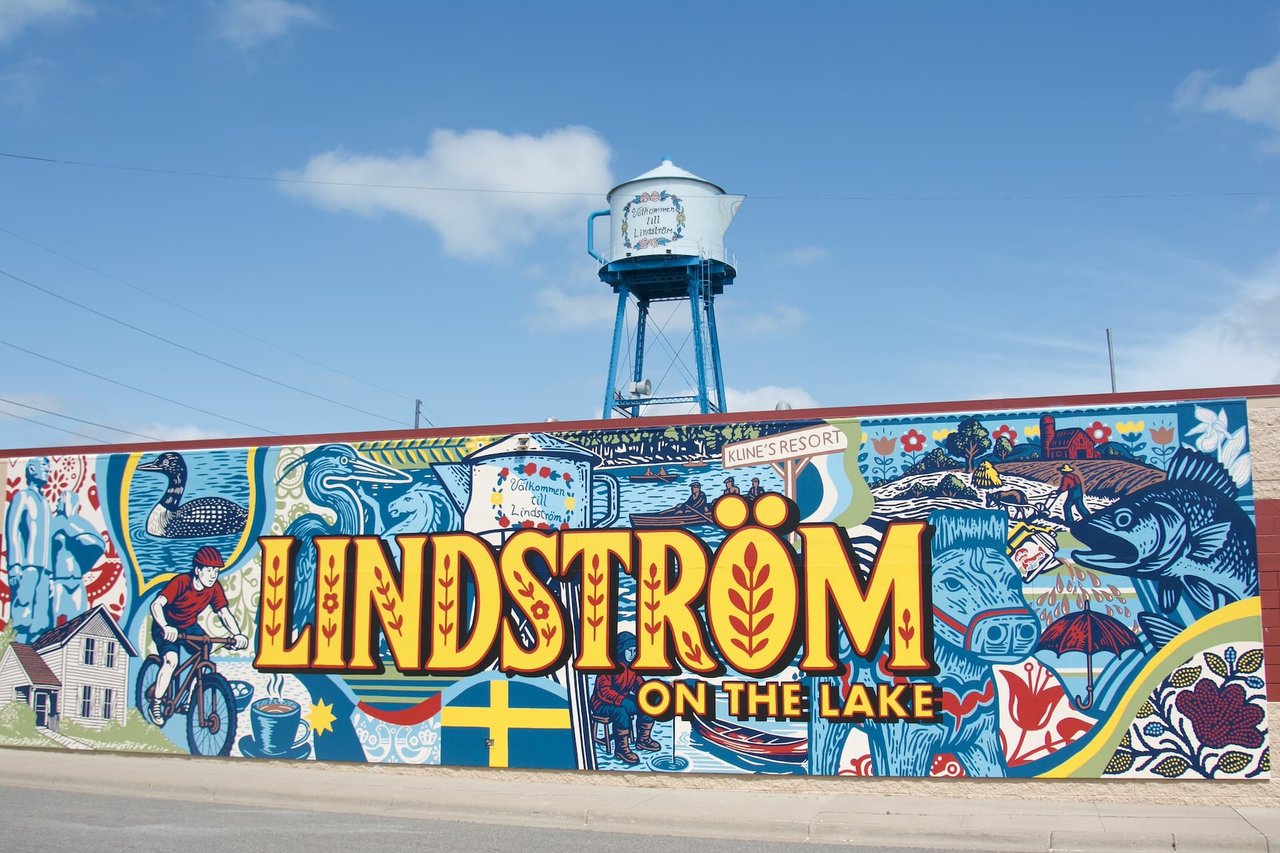 Lindström roadside mural with lake-themed art and a teapot-shaped water tower.