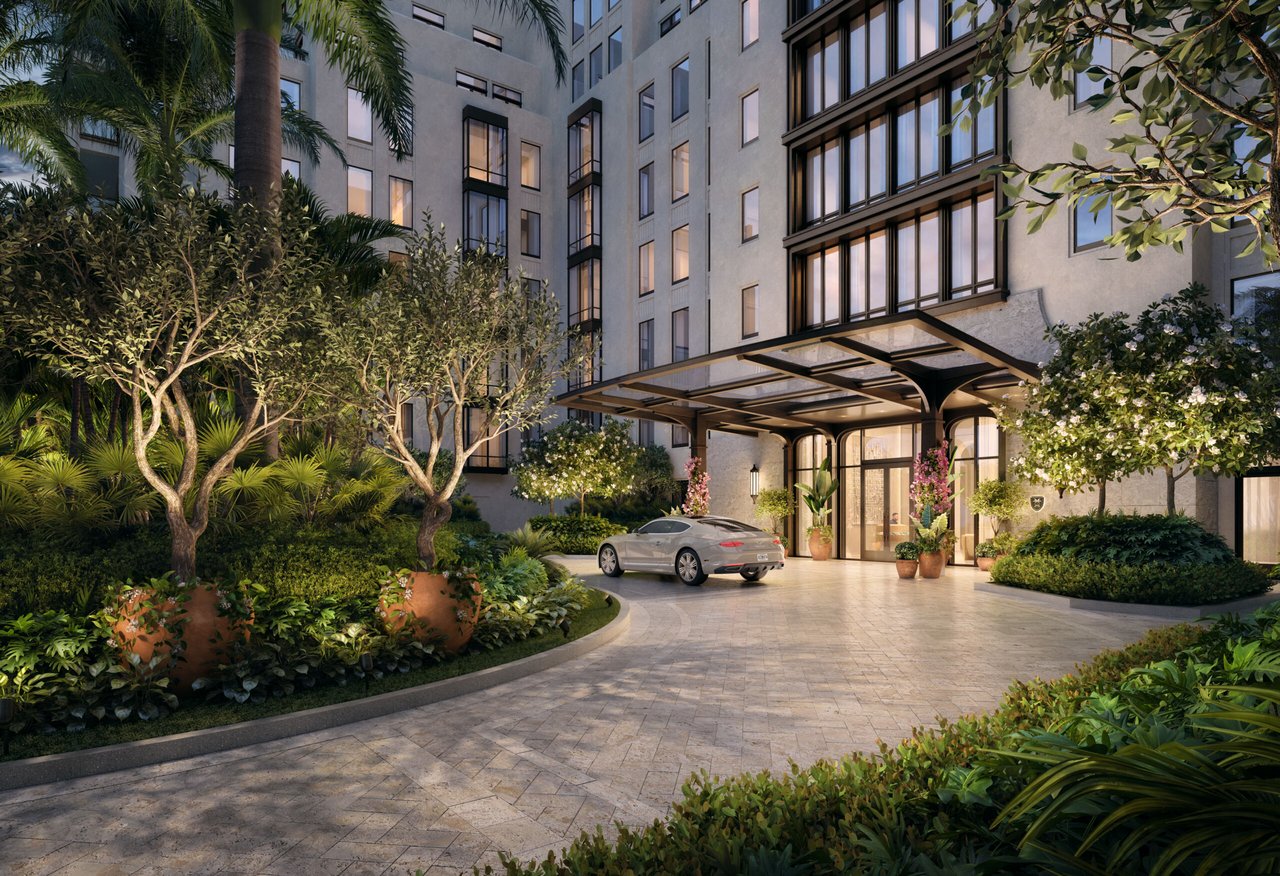 Condominium entrance with a covered porte-cochère, landscaped gardens, and a car in the drive.