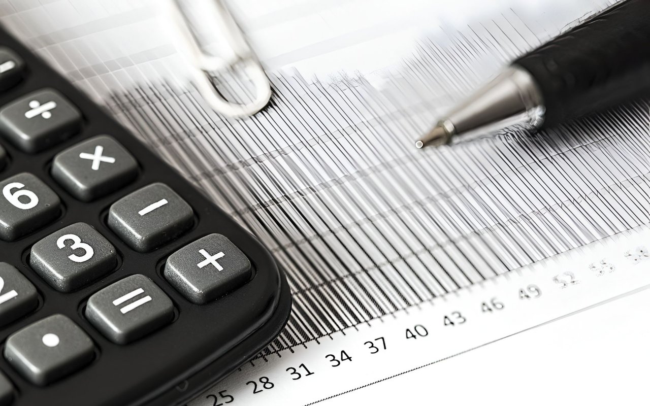 Calculator and pen beside a printed financial chart with a numbered scale.