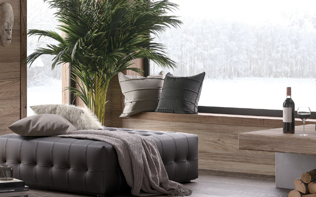 Contemporary living room with a gray tufted sofa beside a picture window overlooking a snowy forest.