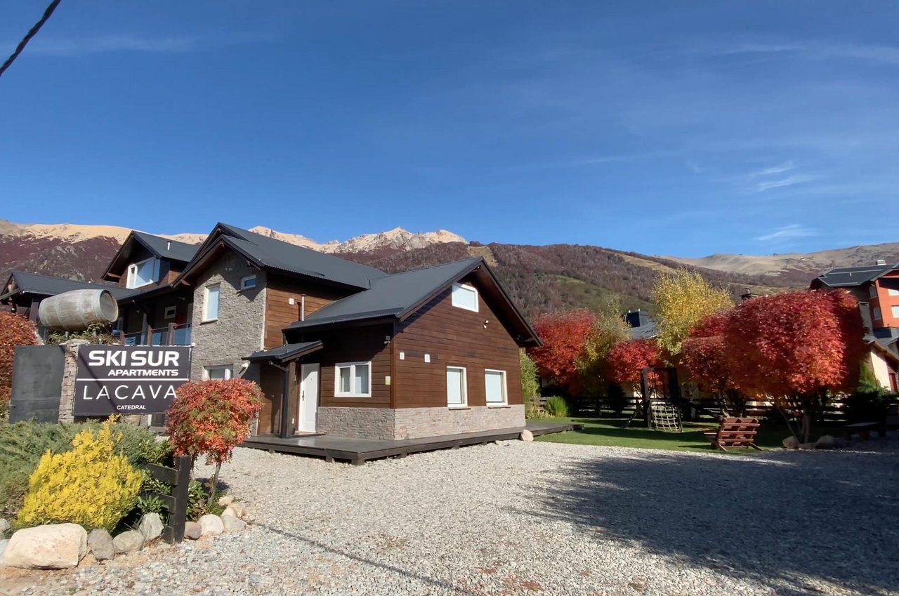 Ski Sur apartment building with timber siding, autumn trees, and mountains in the background.