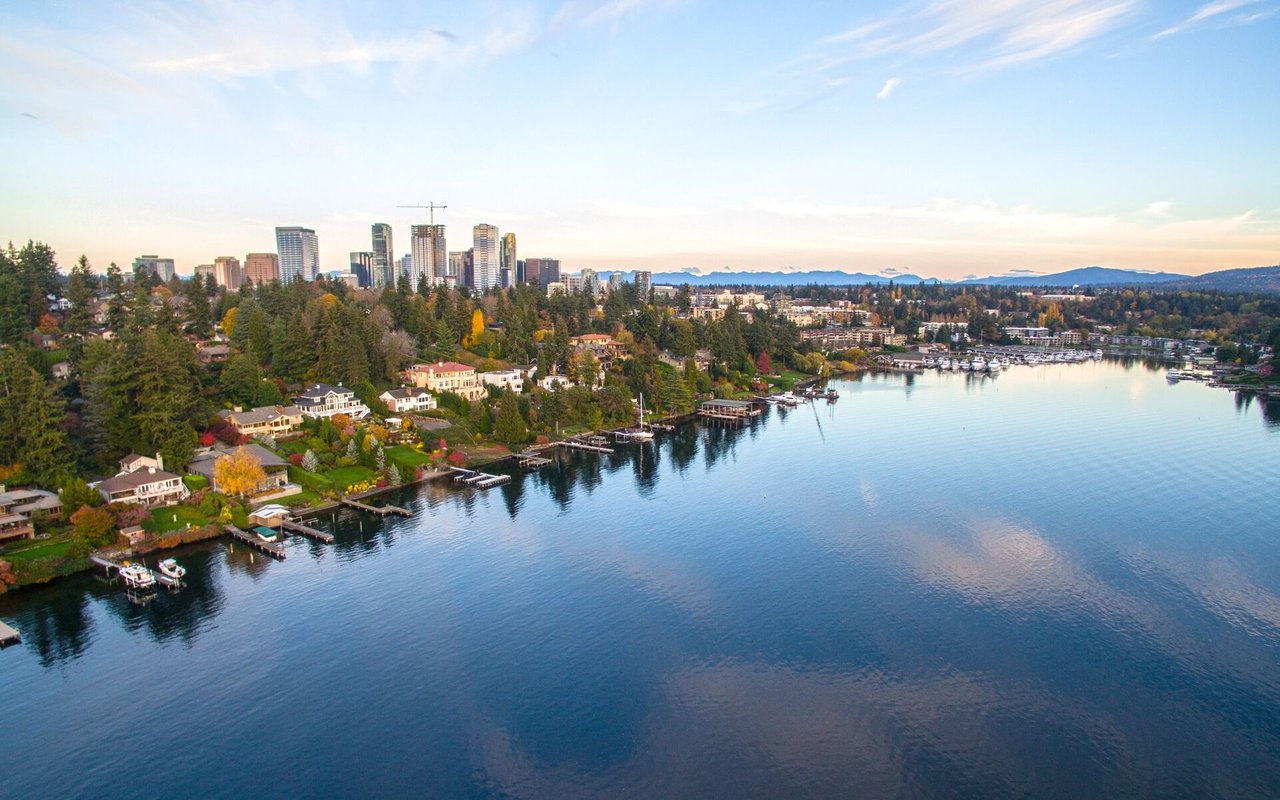 Aerial view of Bellevue’s waterfront homes and marina, with downtown towers and distant mountains.
