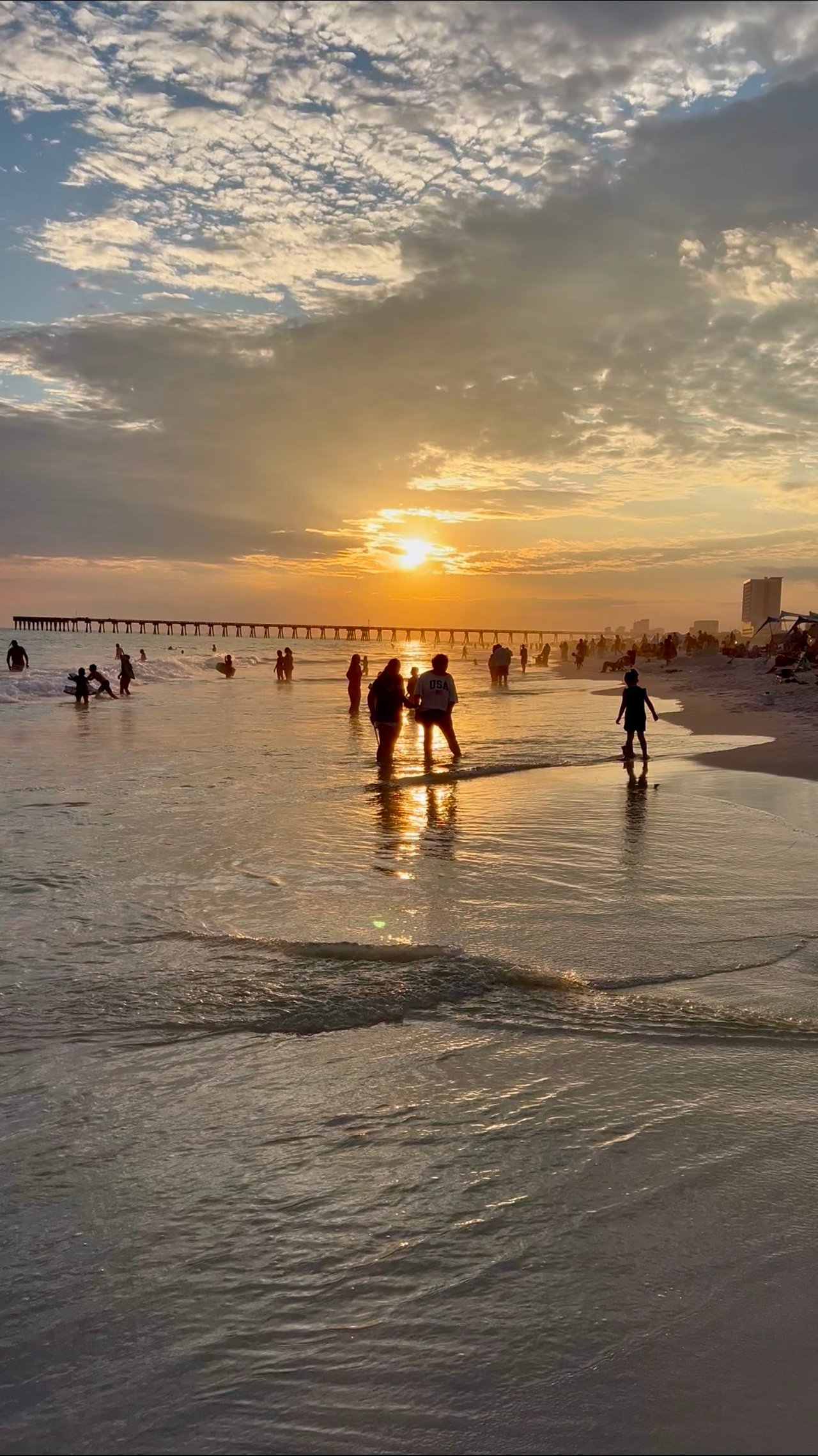 People watching sunset on the beach near MB Miller County Pier in Panama City Beach Florida