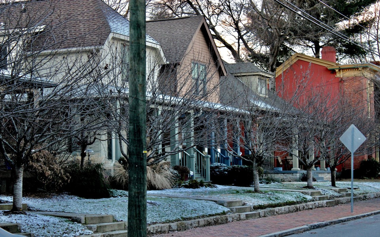 Houses along a winter street, with bare trees and a light dusting of snow.