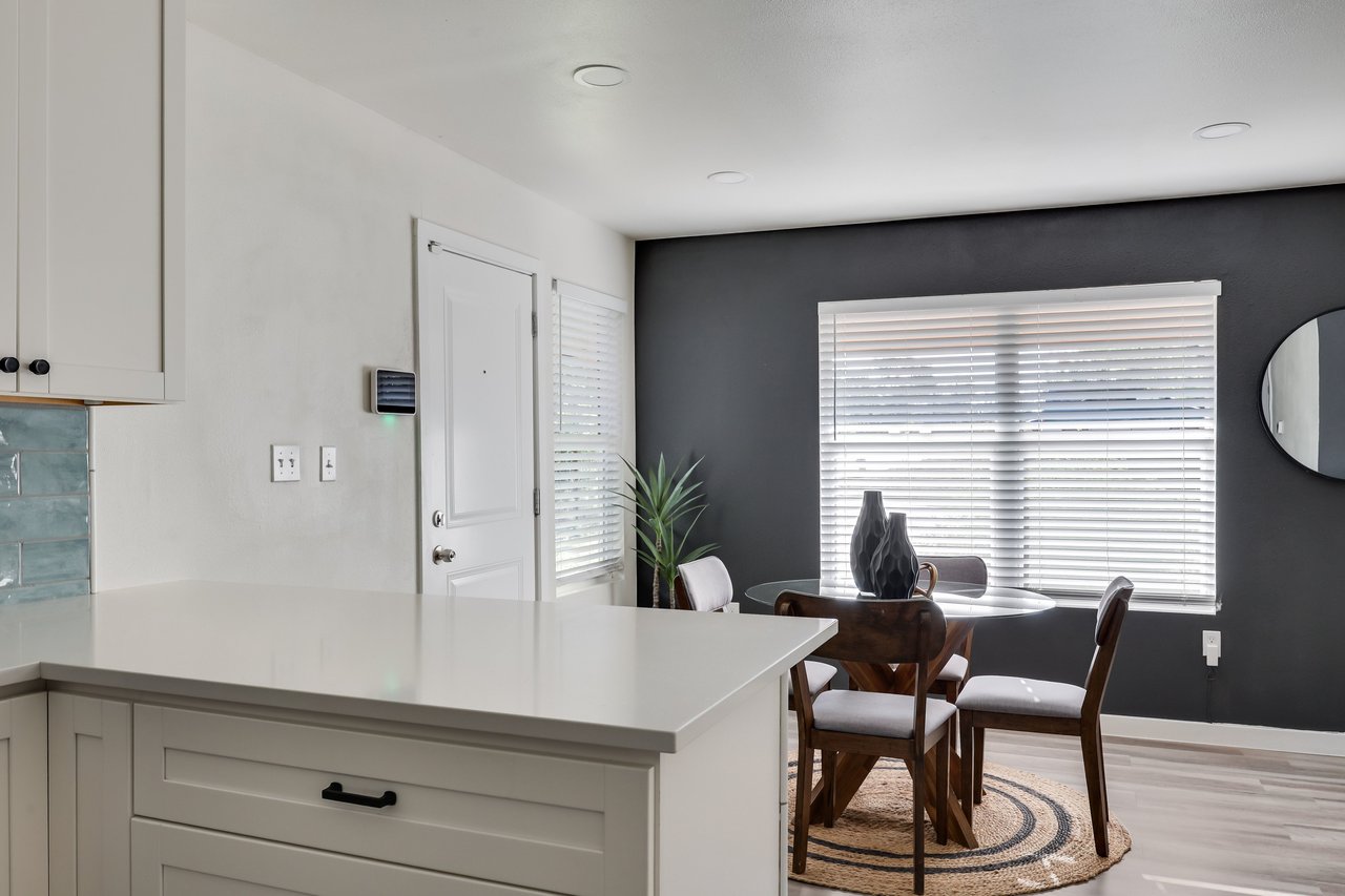 Kitchen island overlooking a round dining table by a large window and charcoal accent wall.