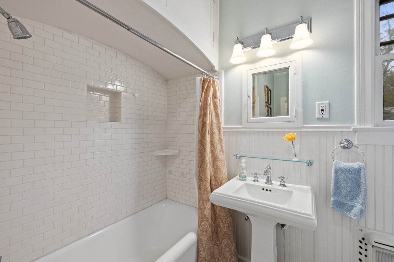Bathroom with a white subway-tile tub surround and pedestal sink.