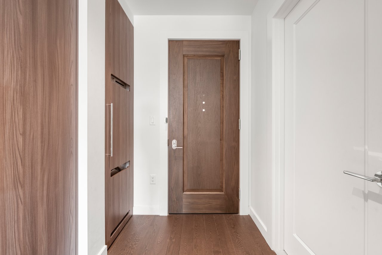 Entry hall with a wood front door, built-in cabinetry, and hardwood floors.