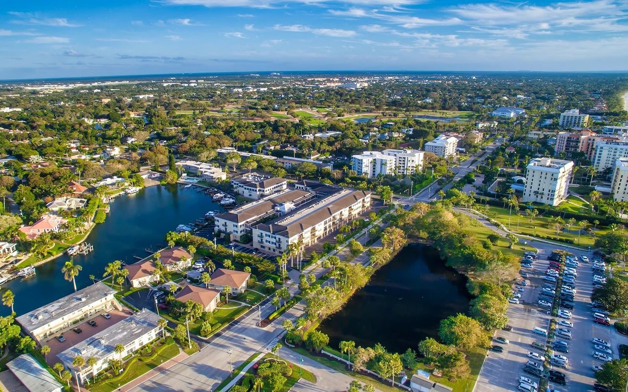 Aerial view of Naples with canals, homes, and the Gulf horizon.