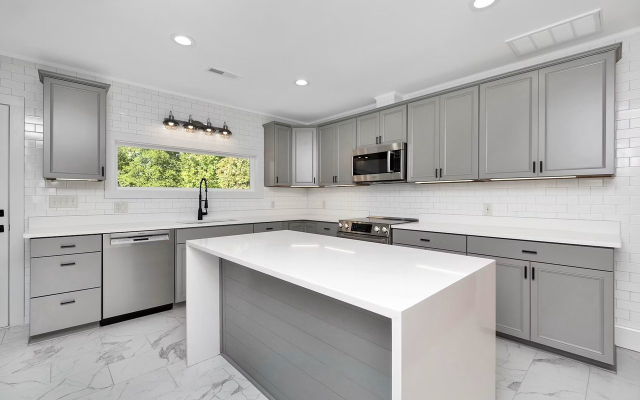 Kitchen with gray shaker cabinets, a large white island, and a long window above the sink.