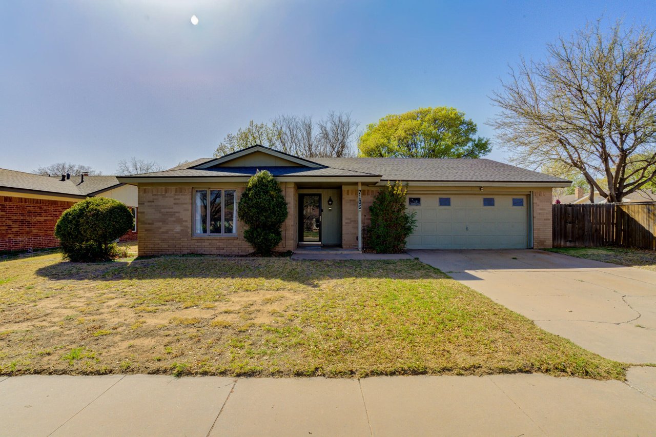 Single-story brick home with an attached garage, covered entry, and broad front lawn.