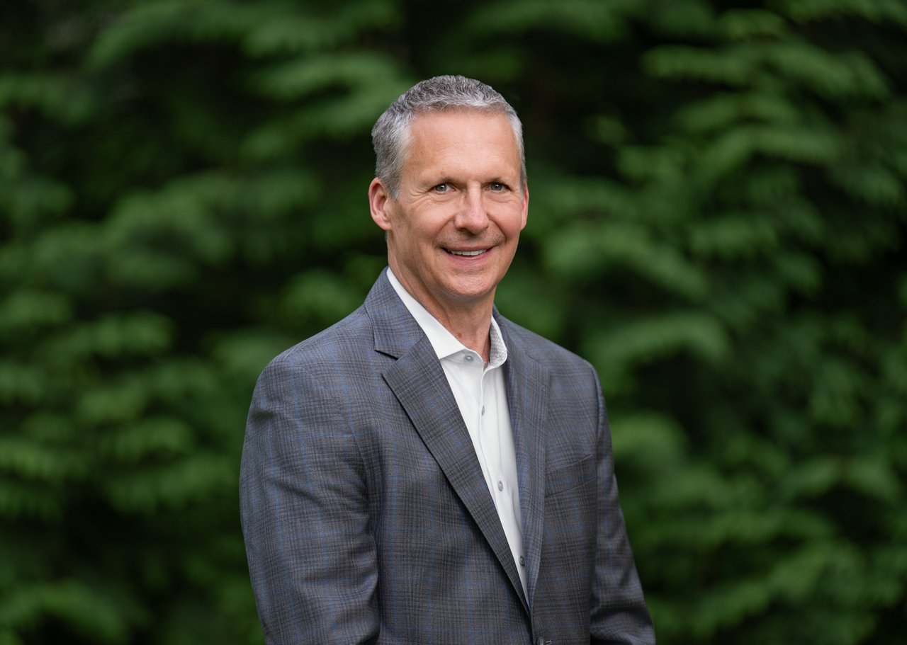 Keith Hovan in a gray checked blazer against leafy greenery