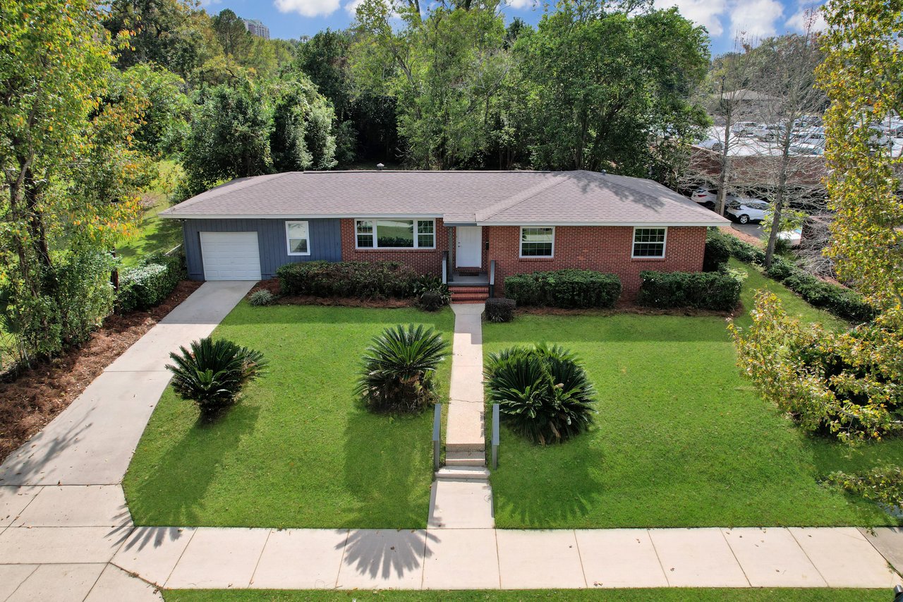 A spacious home surrounded by a large yard and lush trees, creating a serene and inviting outdoor environment.