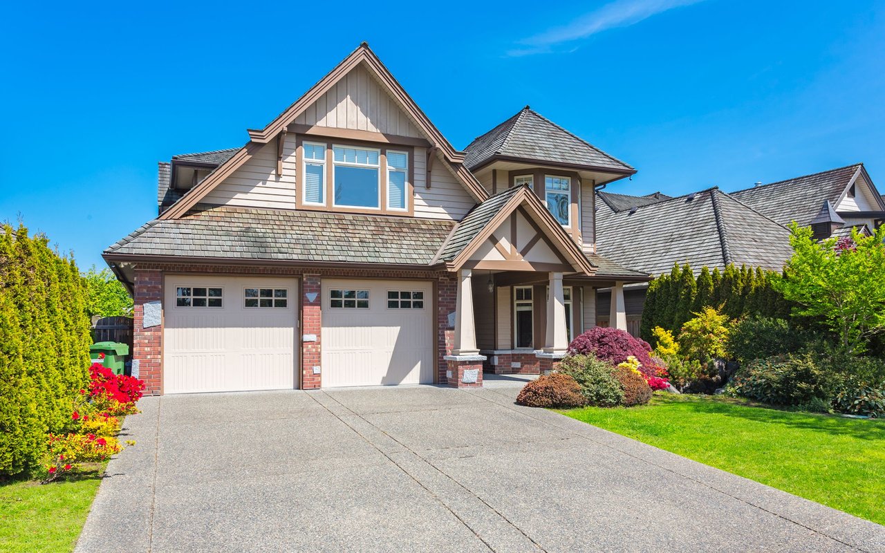 Two-story house with a two-car garage, broad driveway, and landscaped front yard.