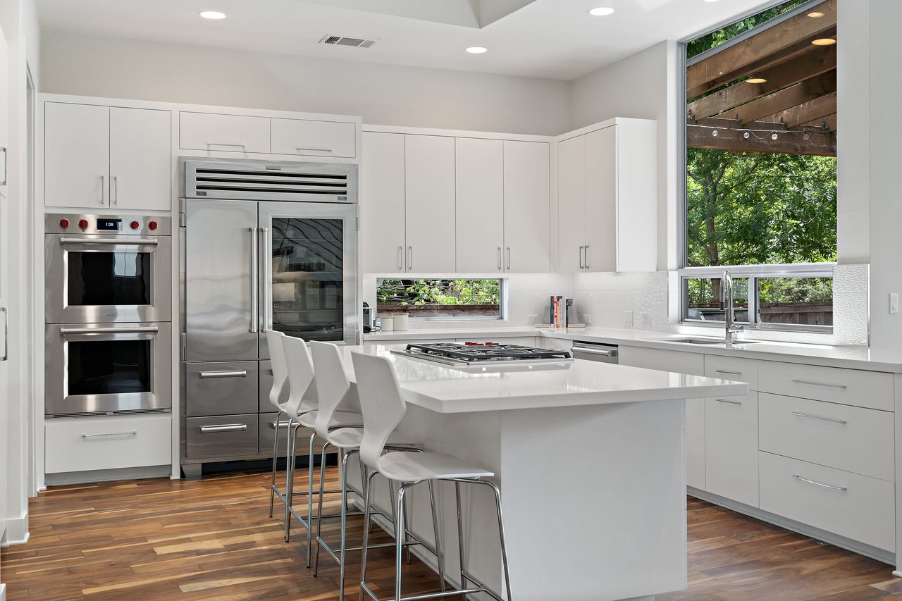 Kitchen with double ovens, white cabinetry, and hardwood floors at 34 Margranita Crescent, Tarrytown, Austin, TX.