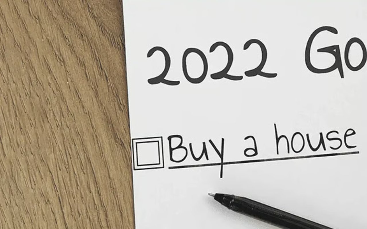 A checklist on a wood surface reads “Buy a house,” with a black pen beside it.