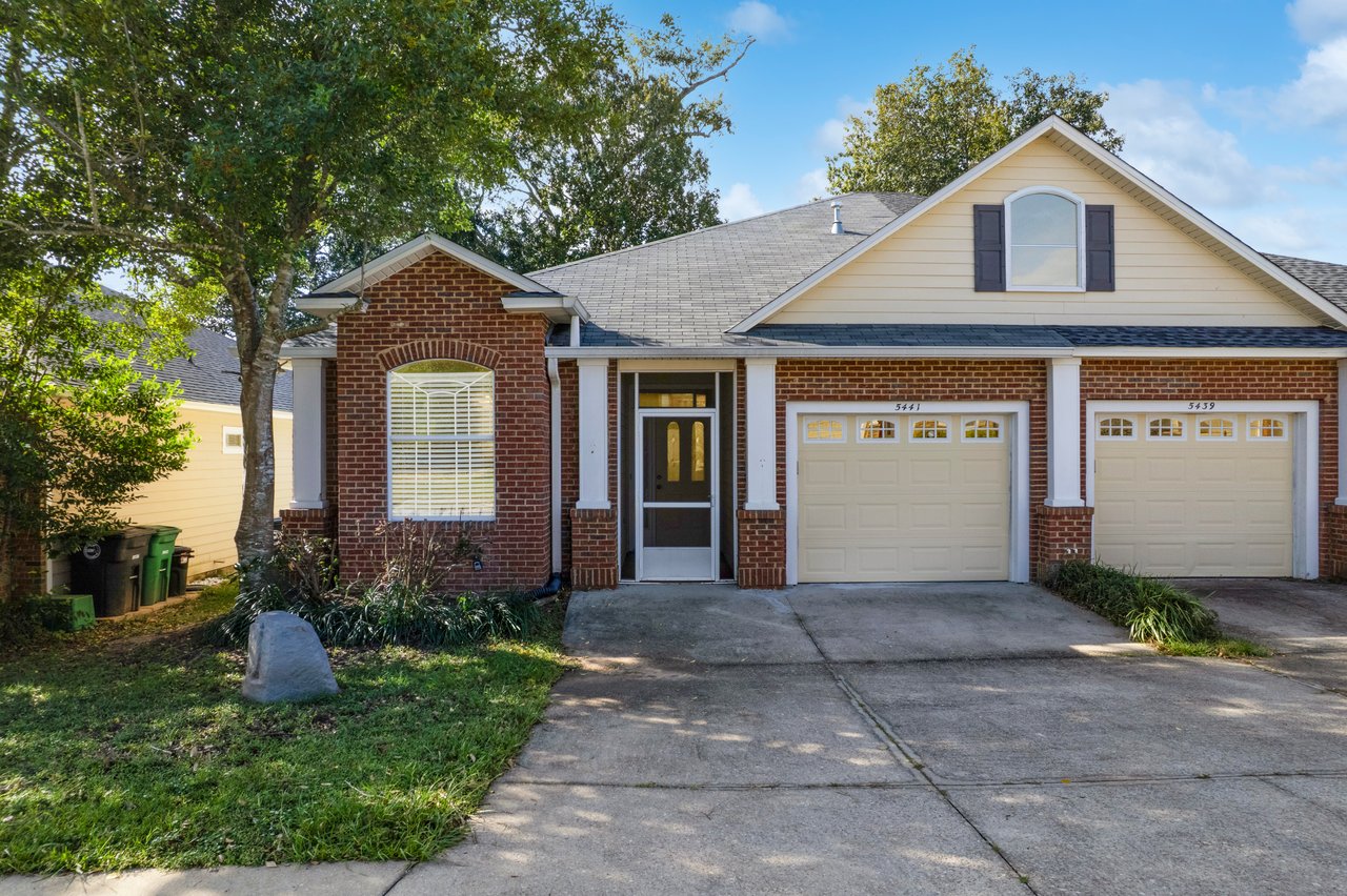 Front exterior view of 5441 Hampton Hill Circle, Tallahassee, Florida 32311 showing brick façade, two-car garage, and landscaped yard.