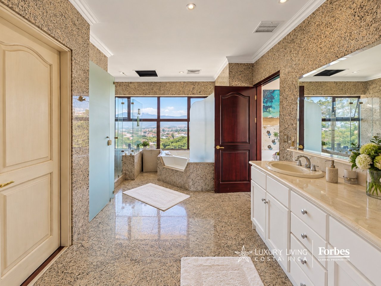 Penthouse bathroom with a soaking tub, double vanity, and wide city and mountain views.