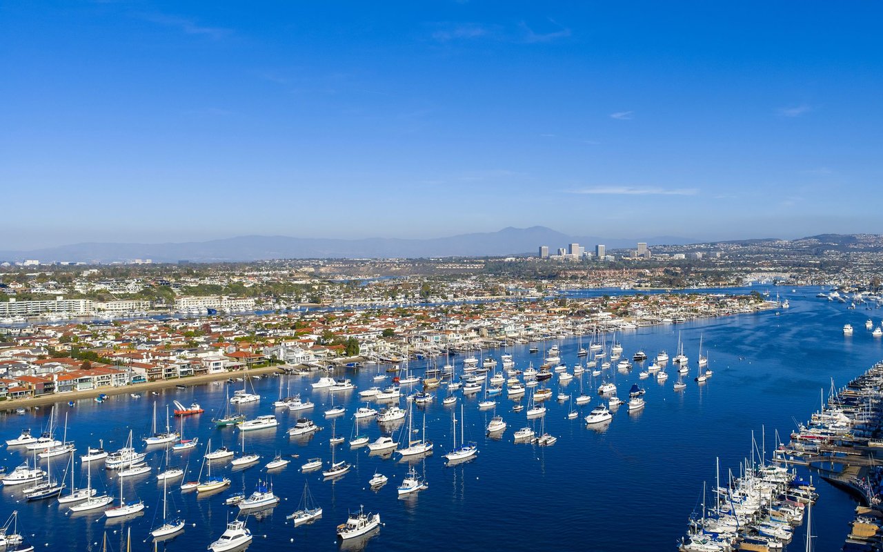 Newport Harbor filled with boats, with waterfront homes and distant hills.
