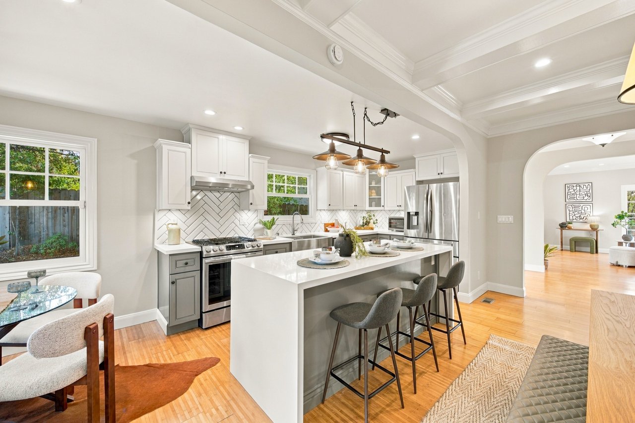 Open-plan kitchen with a large island, white cabinets, herringbone backsplash, and stainless steel appliances.