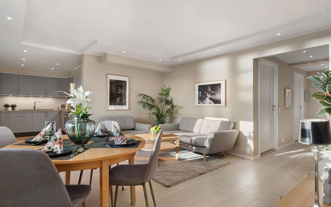 Open-plan living and dining room with a gray kitchen, floral table settings, and gray sofas.