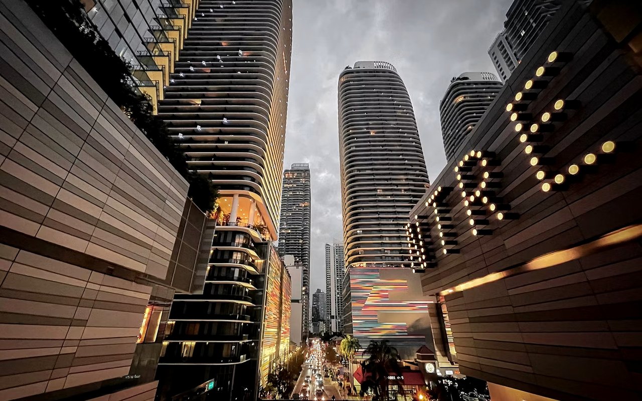 Brickell street lined with modern high-rises and glowing architectural lights at dusk.