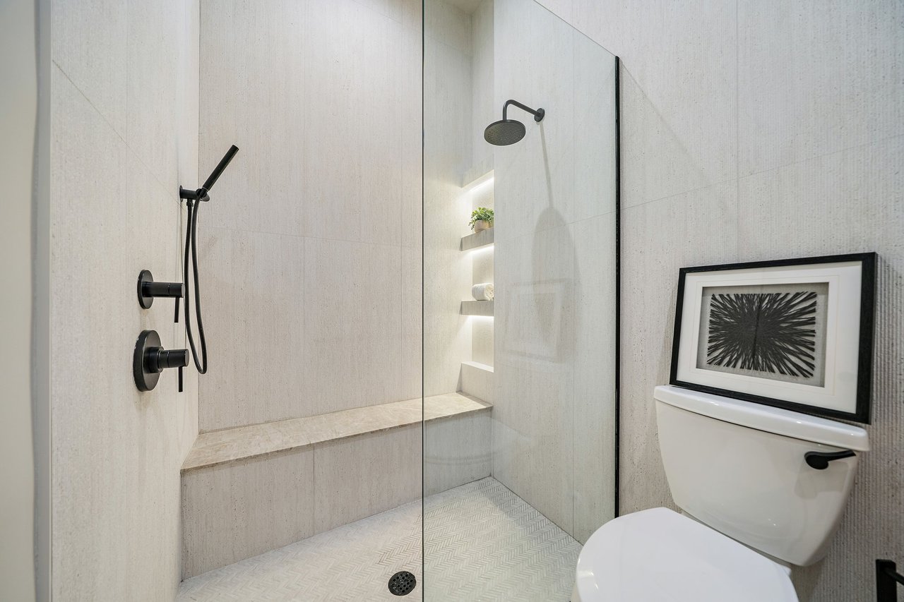 Modern bathroom with a glass-enclosed tiled shower, built-in bench, and matte-black fixtures.