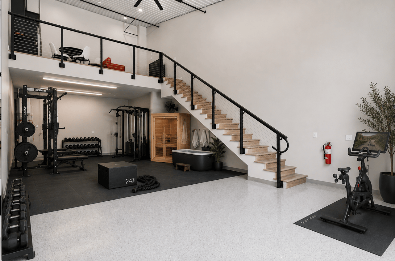 Private home gym and wellness setup inside an Orono garage condo including a squat rack, stationary bike, sauna, and cold plunge tub.