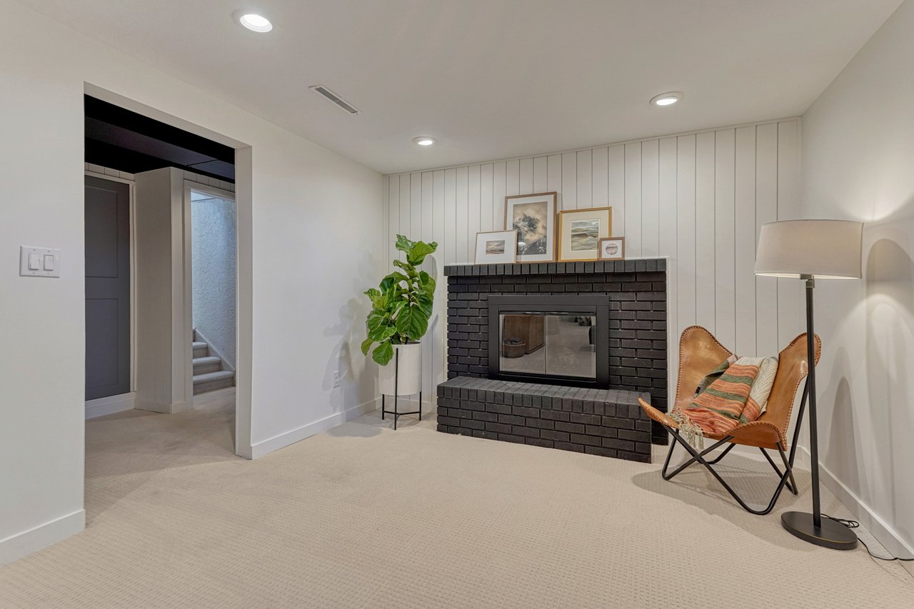 Painted black brick fireplace against a white shiplap wall in the lower-level family room