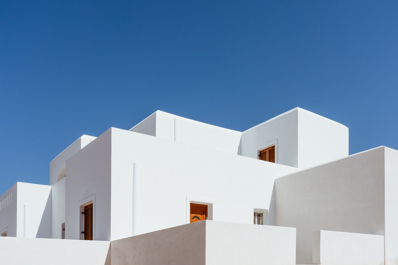 White geometric condo buildings with wooden doors against a clear blue sky.