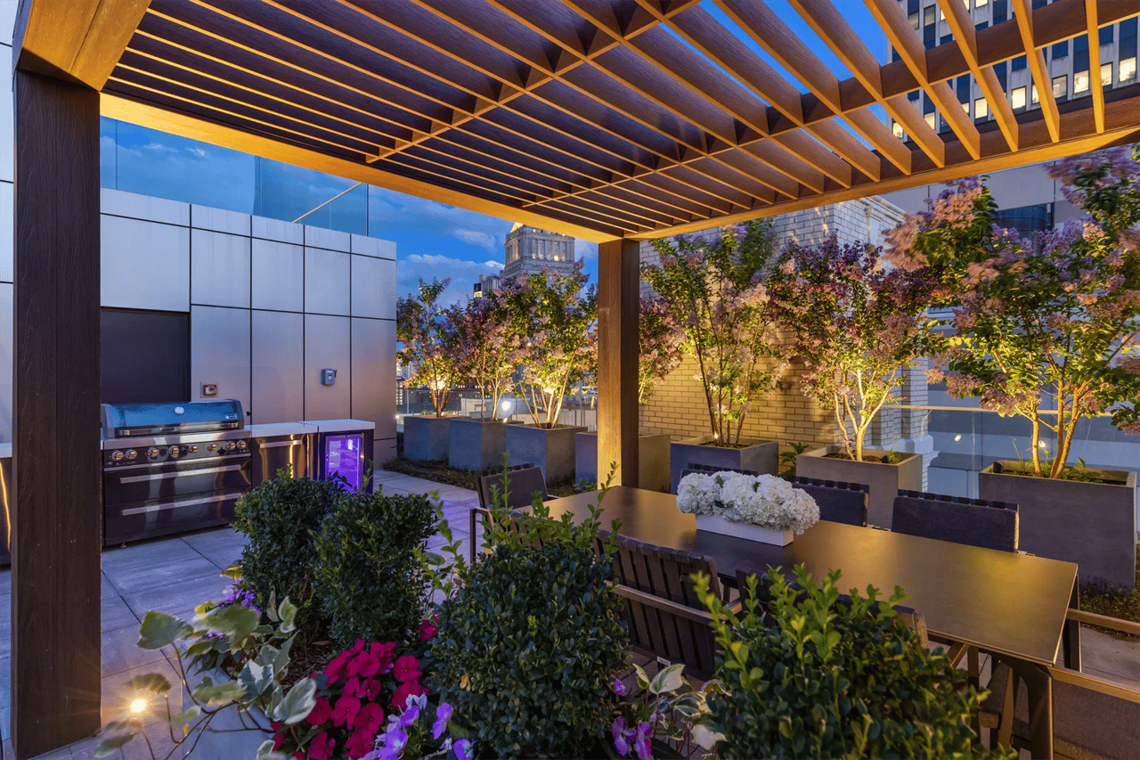 Rooftop terrace with a timber pergola, outdoor dining area, grill, and landscaped planters.